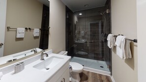Un baño moderno con cabina de ducha de vidrio, tocador doble y retrete.