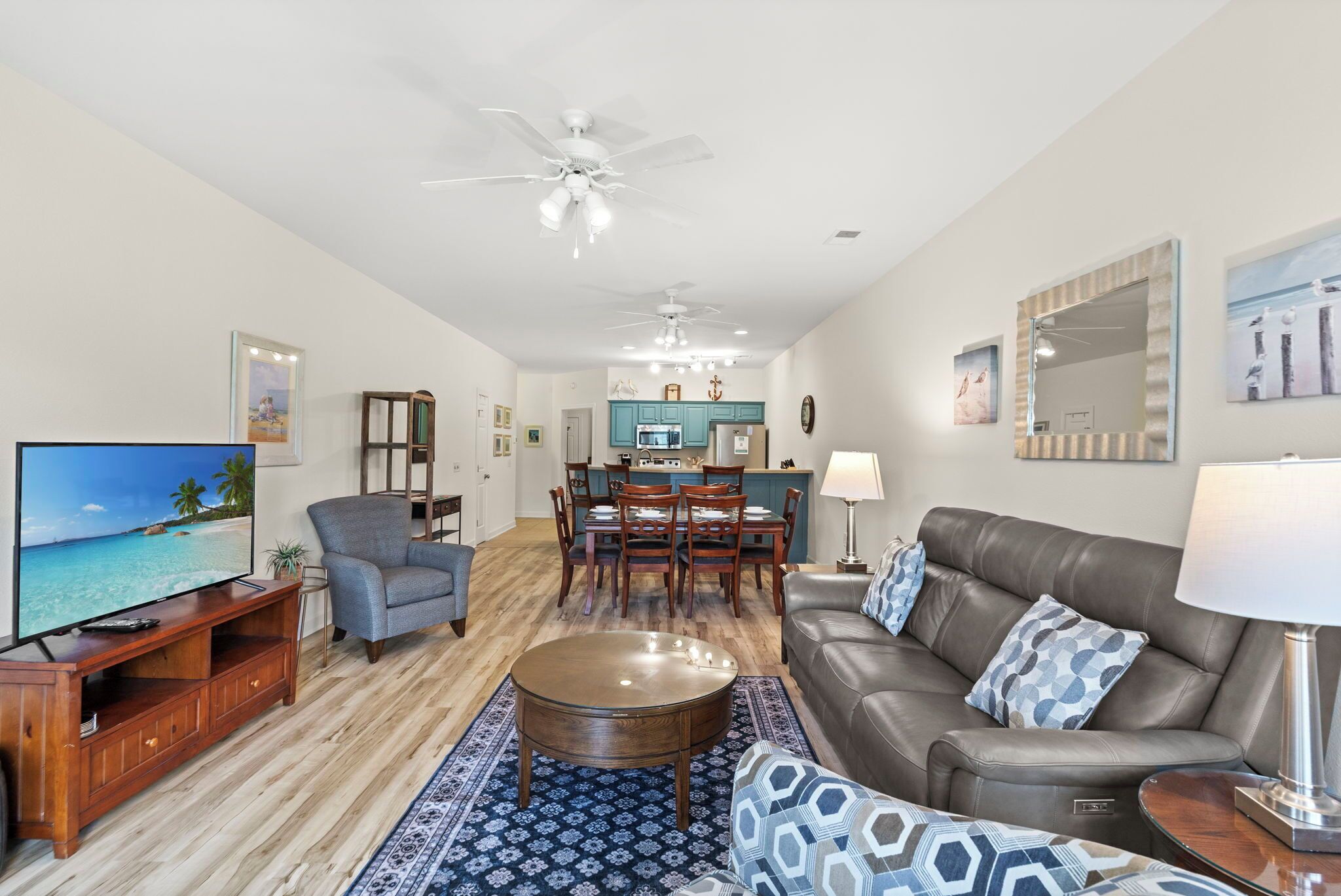 A living room with a TV, sofa, coffee table, and a dining area with chairs and a table.