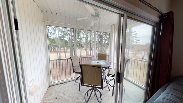 A covered patio with a table and chairs, a ceiling fan, and a view of trees. - Champions Unit 3417 (Sunset Beach)