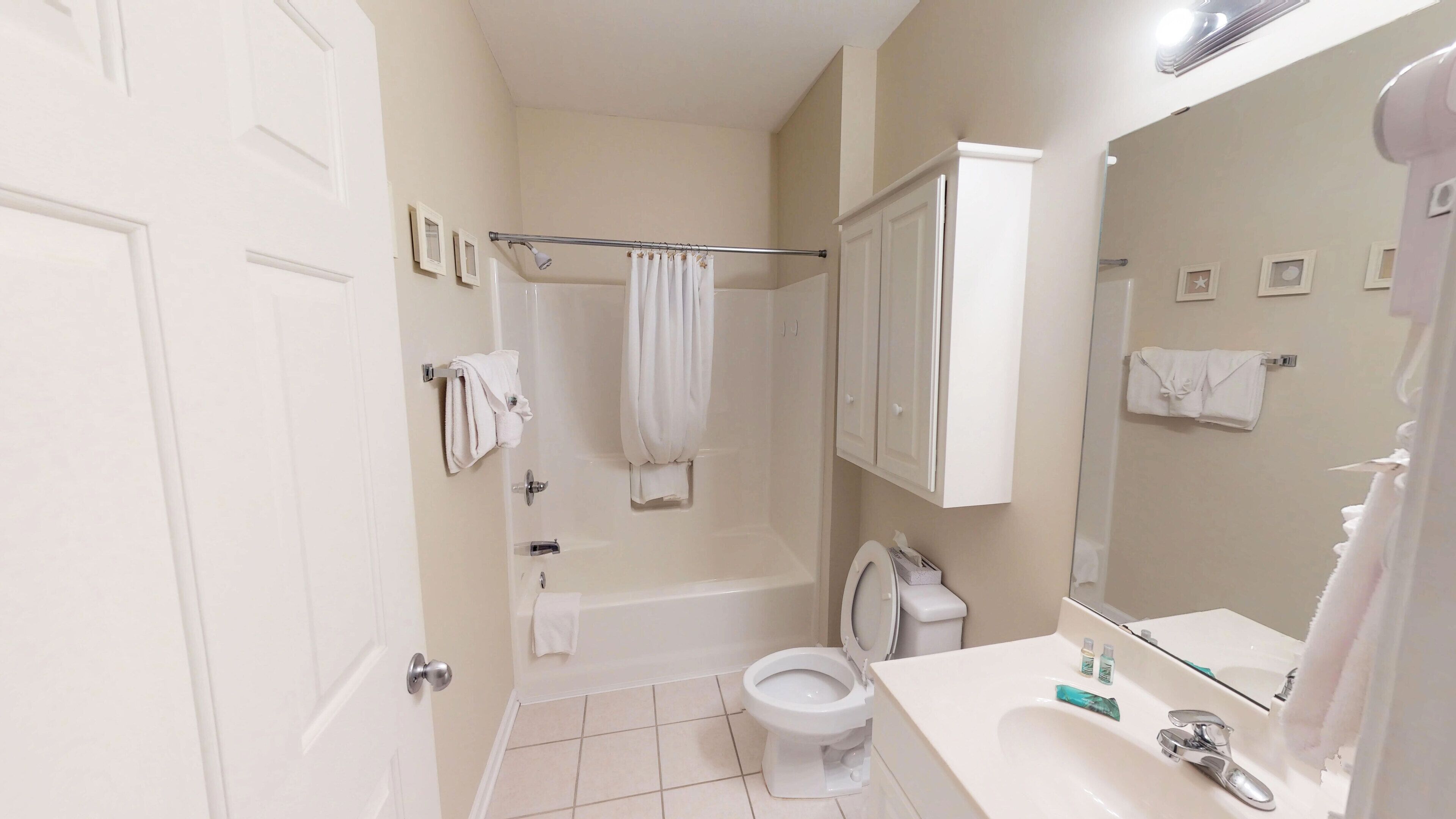 A bathroom with a toilet, sink, mirror, and shower.