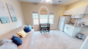 A compact living space with a kitchenette, a dining area with a table and chairs, and a sofa with cushions. - Champions Unit 3417 (Sunset Beach)