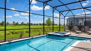 Piscina com vista para um campo de golfe, área de estar coberta e céu azul límpido.