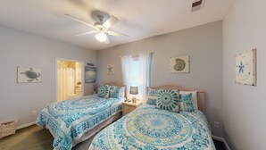 A bedroom with two beds, a ceiling fan, and artwork on the walls. - Champions Unit 3509 (Sunset Beach)