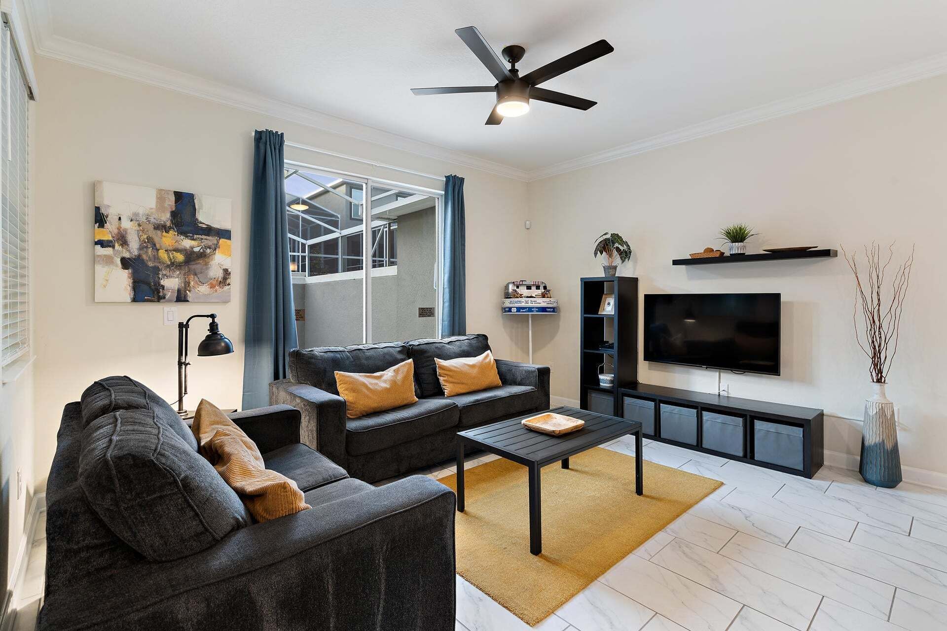 Ein modernes Wohnzimmer mit einer Sofagarnitur, einem Couchtisch, einem Fernseher und einem Deckenventilator.