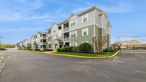 Una hilera de edificios de apartamentos de varios pisos con balcones, un estacionamiento y un cielo despejado.