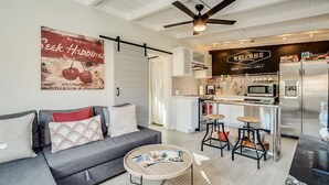 A modern kitchen with a bar area, a dining table with stools, and a living area with a sofa and a coffee table. - Chic Duplex in Tucson 1 of 2 (Tucson)