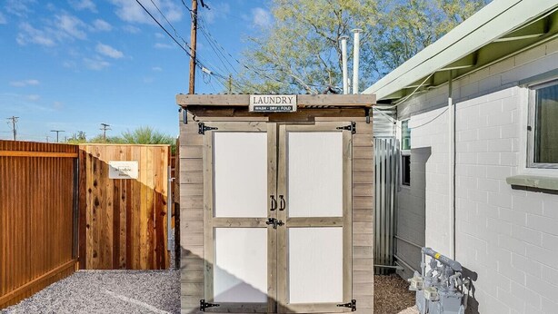 A laundry facility with a wooden exterior and a sign indicating services like wash, dry, and fold. - Chic Duplex in Tucson 1 of 2 (Tucson)