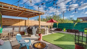 A backyard with a wooden pergola, outdoor seating, a fire pit, and string lights. - Chic Duplex in Tucson 1 of 2 (Tucson)