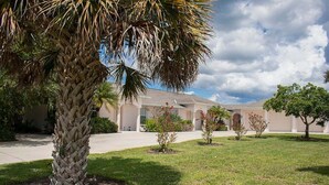 A residential area with a palm tree, a house with a driveway, and a clear sky. - Chd3583-c (Rotonda West)