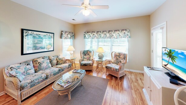 A living room with a sofa, armchairs, a coffee table, and a TV. - Club Villas Unit 25A - Lower Level (Sunset Beach)