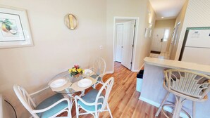 A dining area with a glass table, white chairs, and a vase of yellow flowers. - Club Villas Unit 25A - Lower Level (Sunset Beach)