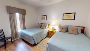 Une chambre double avec deux lits, une table de chevet, une chaise et une fenêtre avec des rideaux.