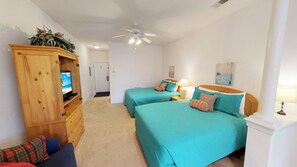 A bedroom with two beds, a wooden cabinet with a TV, and a ceiling fan. - Champions Unit 3702 (Sunset Beach)