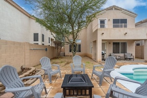 A backyard with a pool, patio furniture, and a tree.