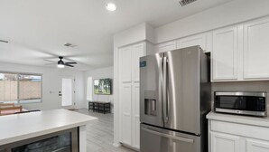 A modern kitchen with white cabinetry, a stainless steel refrigerator, and a microwave. - City Escape in Goodyear w Pool Spring Training (Goodyear)