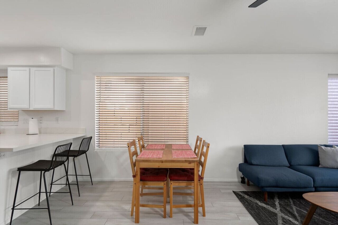 A modern living space with a dining area, a sofa, and a kitchen counter.