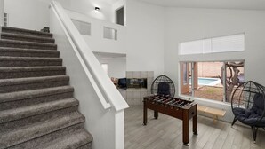 A modern interior with a staircase, a foosball table, and a view of a backyard. - City Escape in Goodyear w Pool Spring Training (Goodyear)
