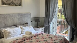 A neatly made bed with a floral bedspread, a headboard, a bedside lamp, a small table with a lamp, and a large framed map on the wall. - Guest House Maison Indipendenza (Rome)