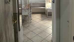A narrow hallway with a tiled floor leading to a room with a bed, a chair, and a desk. There is a door on the left with a brass handle and a number '10' above it. - Guest House Maison Indipendenza (Rome)