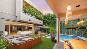 A modern outdoor living space with a pool, a wooden deck, and a built-in seating area. - Luxurious Villa in The Heart Of Beverly Hills/West Hollywood (Beverly Hills)