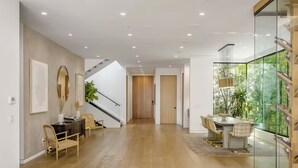 A modern interior with a wooden floor, a staircase, a dining area with a glass partition, and a view of greenery through the glass. - Luxurious Villa in The Heart Of Beverly Hills/West Hollywood (Beverly Hills)