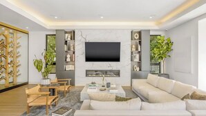 A modern living room with a large flat-screen TV, a fireplace, and a bookshelf. - Luxurious Villa in The Heart Of Beverly Hills/West Hollywood (Beverly Hills)