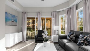 Una sala moderna con una mesa de centro blanca, un sofá negro y una orquídea en maceta.