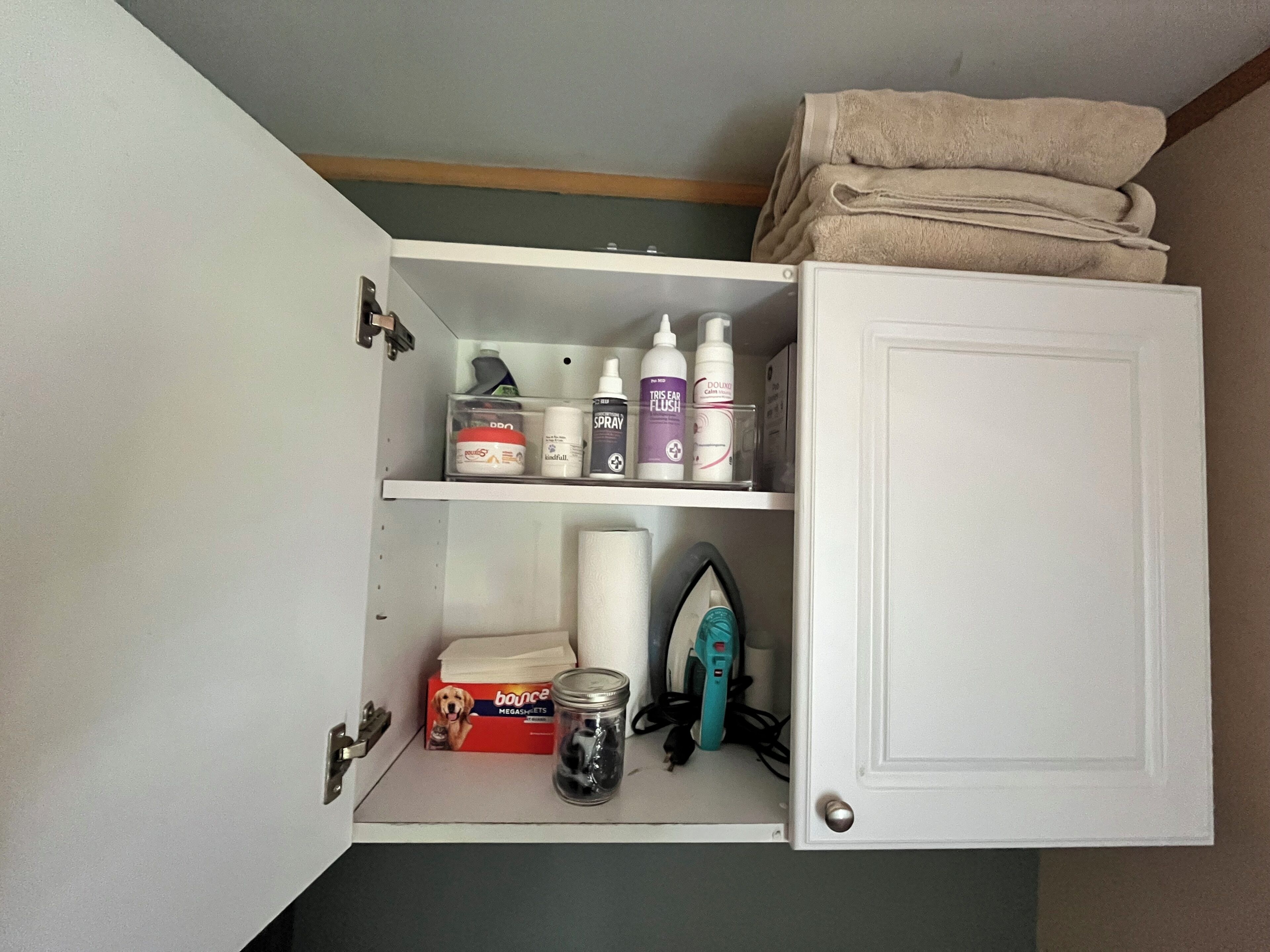 Une salle de bain avec une pile de serviettes, une boîte de préservatifs, un vaporisateur et un fer à repasser.
