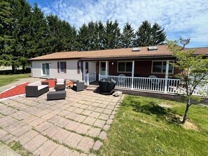 Ein einstöckiges Haus mit überdachter Terrasse, Gartenmöbeln und einer Satellitenschüssel.