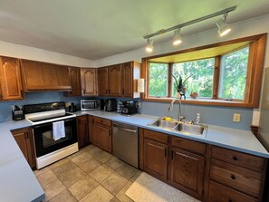 A modern kitchen with wooden cabinets, a stainless steel sink, and a window with a view of greenery. - Secluded Finger Lakes 3BR Retreat Near Keuka Lake with Vineyard Views (Branchport)