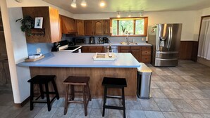 A modern kitchen with a large island, wooden cabinets, stainless steel appliances, and a window providing natural light. - Secluded Finger Lakes 3BR Retreat Near Keuka Lake with Vineyard Views (Branchport)