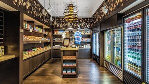 A store with shelves stocked with snacks, a display counter, and refrigerated beverage cases. - 5203 (Orlando)