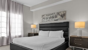 A modern bedroom with a large bed, two bedside tables, a headboard, and a wall-mounted artwork. - 5203 (Orlando)