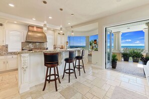 A kitchen with a large island, bar stools, and a view of the ocean. - 4 Bedroom Beach Bliss (Palm Coast)