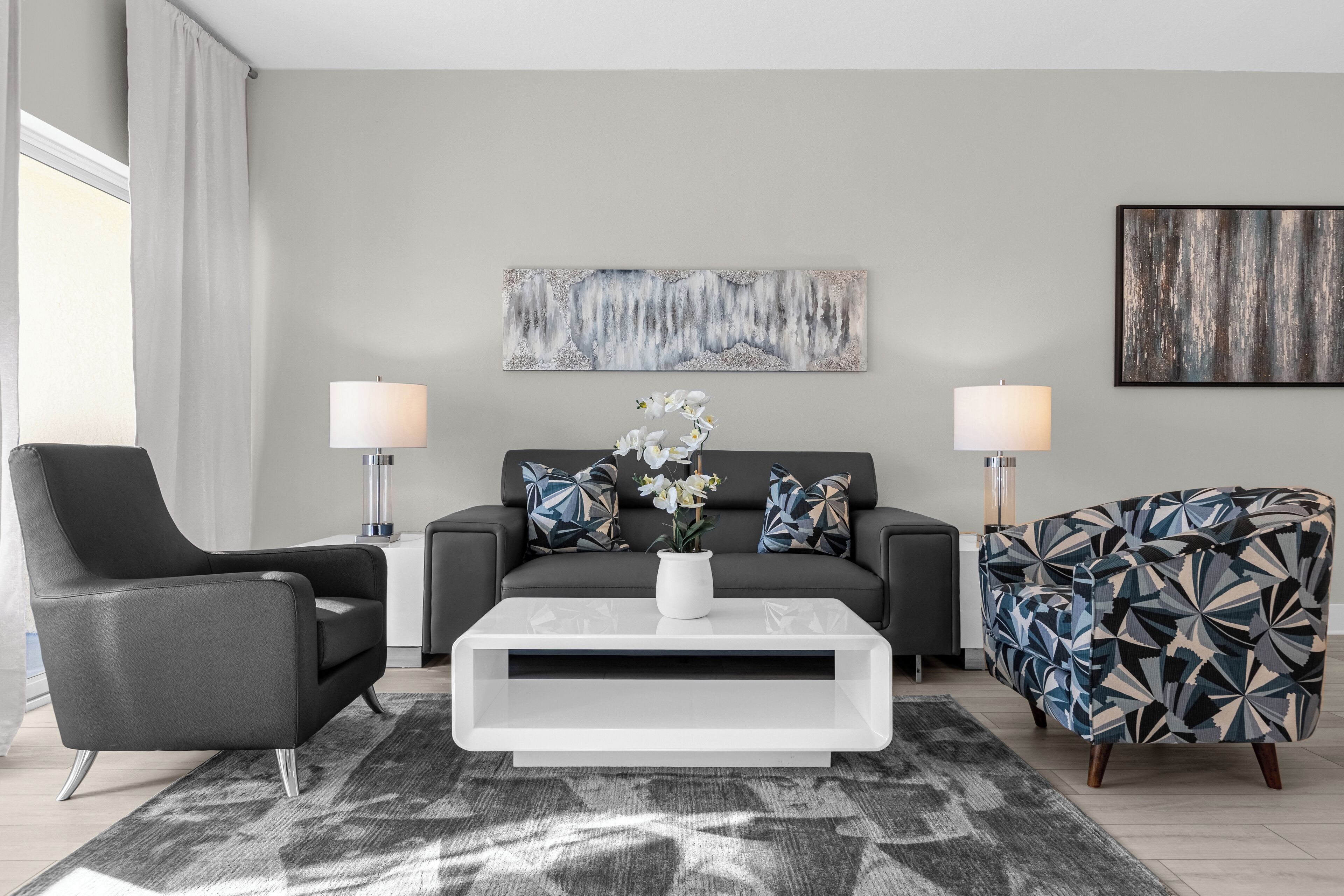 A modern living room with a sofa, two armchairs, a coffee table, and a rug.