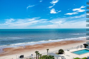 A beach view with a pool and a building with balconies. - Aliki Atrium Beachfront Condo (Ormond Beach)