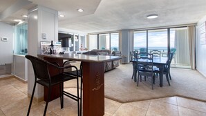 Ampla sala de estar com bar, assentos e vista para o oceano.