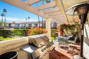 Eine Terrassenausstattung mit Grill, Gartenmöbeln und Blick auf eine Wohngegend.