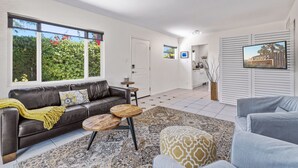 A modern living room with a leather sofa, wooden coffee table, and patterned rug. - San Miguel (Palm Springs)