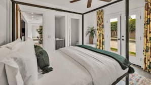A four-poster bed with white linens, a ceiling fan, and a view of the outdoors through glass doors. - Sunny Dunes (Palm Springs)