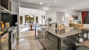 A modern kitchen with stainless steel appliances, a marble countertop, and a central island. - Sunny Dunes (Palm Springs)