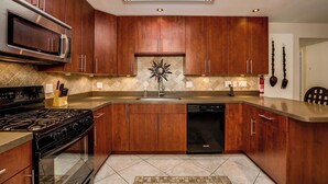 Une cuisine moderne avec des meubles en bois, des appareils électroménagers en acier inoxydable et un îlot central.