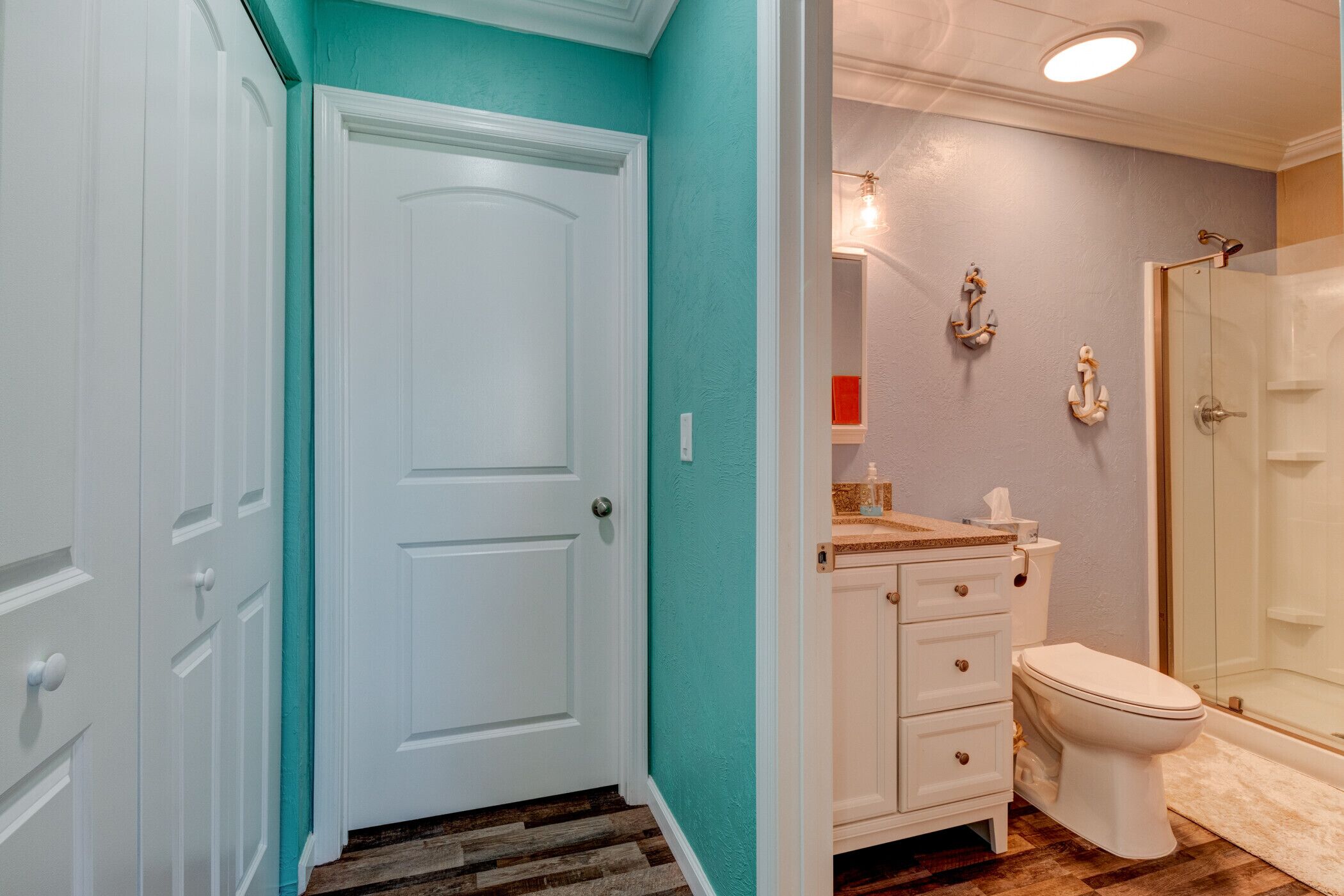 Une salle de bain avec une porte blanche, des toilettes, un lavabo avec un plan de travail et un espace douche.