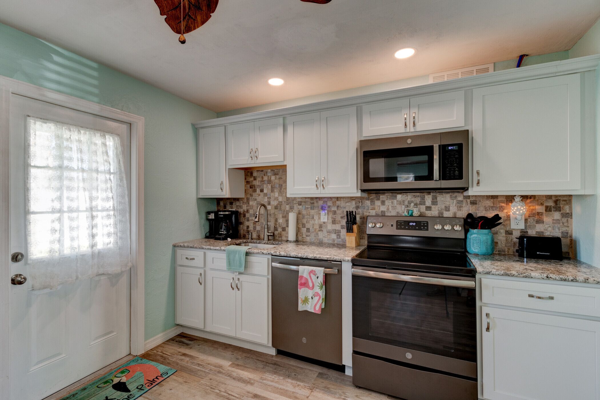 A kitchen with white cabinets, a stainless steel oven, a microwave, and a dishwasher.