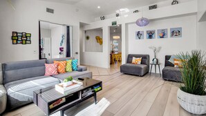 Un salon moderne avec un canapé gris, une table basse et un coin repas à l’arrière-plan.