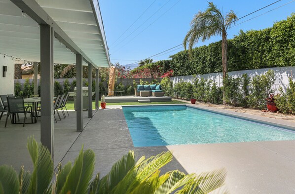 A covered outdoor area with a pool, seating, and greenery. - Viminal (Palm Springs)