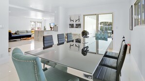 Een moderne eetruimte met een glazen tafel, zwarte en teal stoelen en uitzicht op het buitenterras.