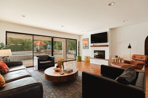 Ein modernes Wohnzimmer mit Kamin, Ledersofas, einem Couchtisch und einem Fernseher.
