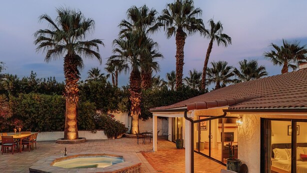 Un área de patio con jacuzzi, asientos y un pozo de fuego.