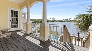 Une terrasse couverte avec vue sur un lac, une piscine et une chaise.
